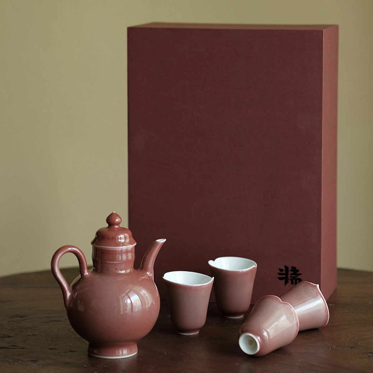 Rose ceramic teapot and four petal-rim cups beside a matching box