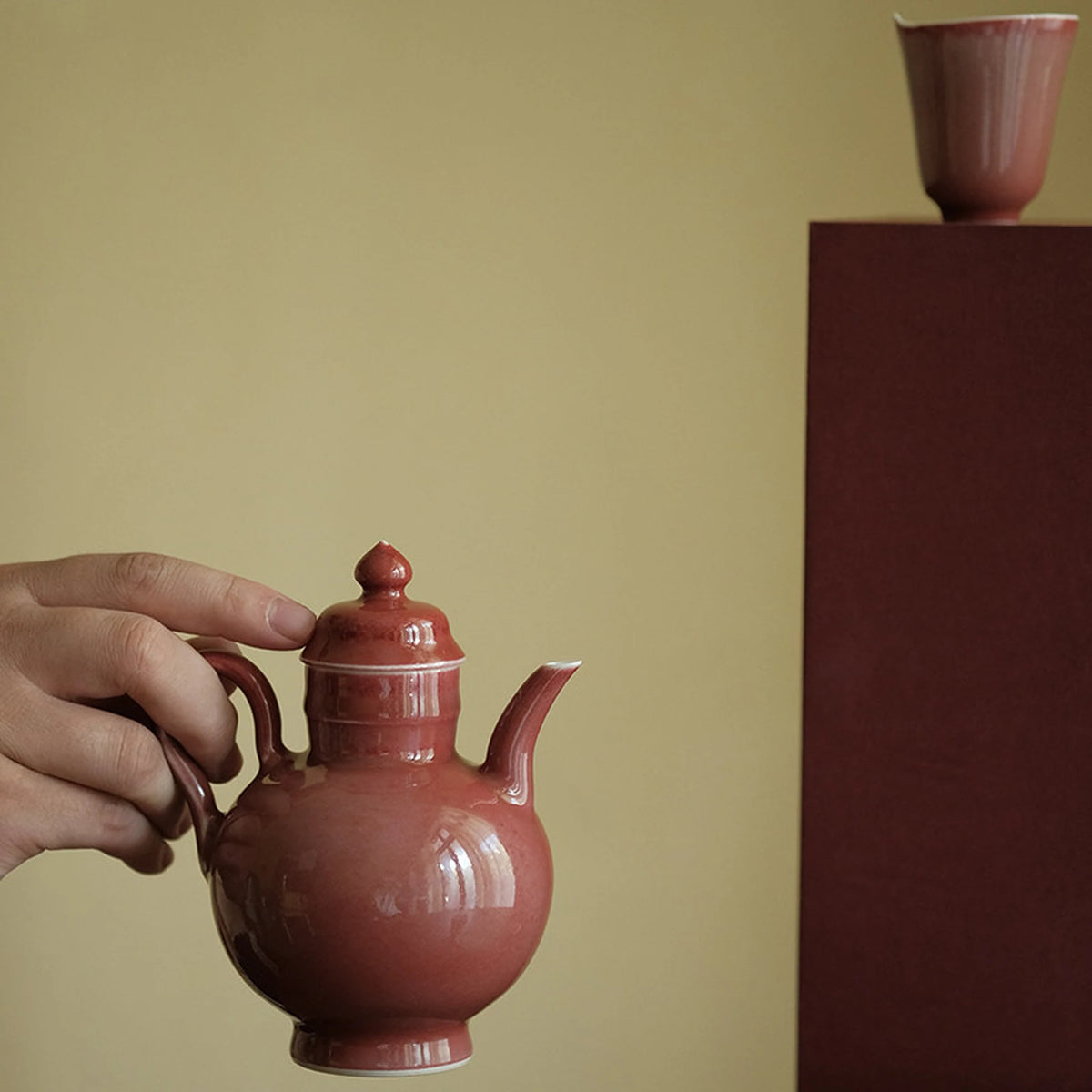 Hand holding the rose glaze teapot beside a matching cup