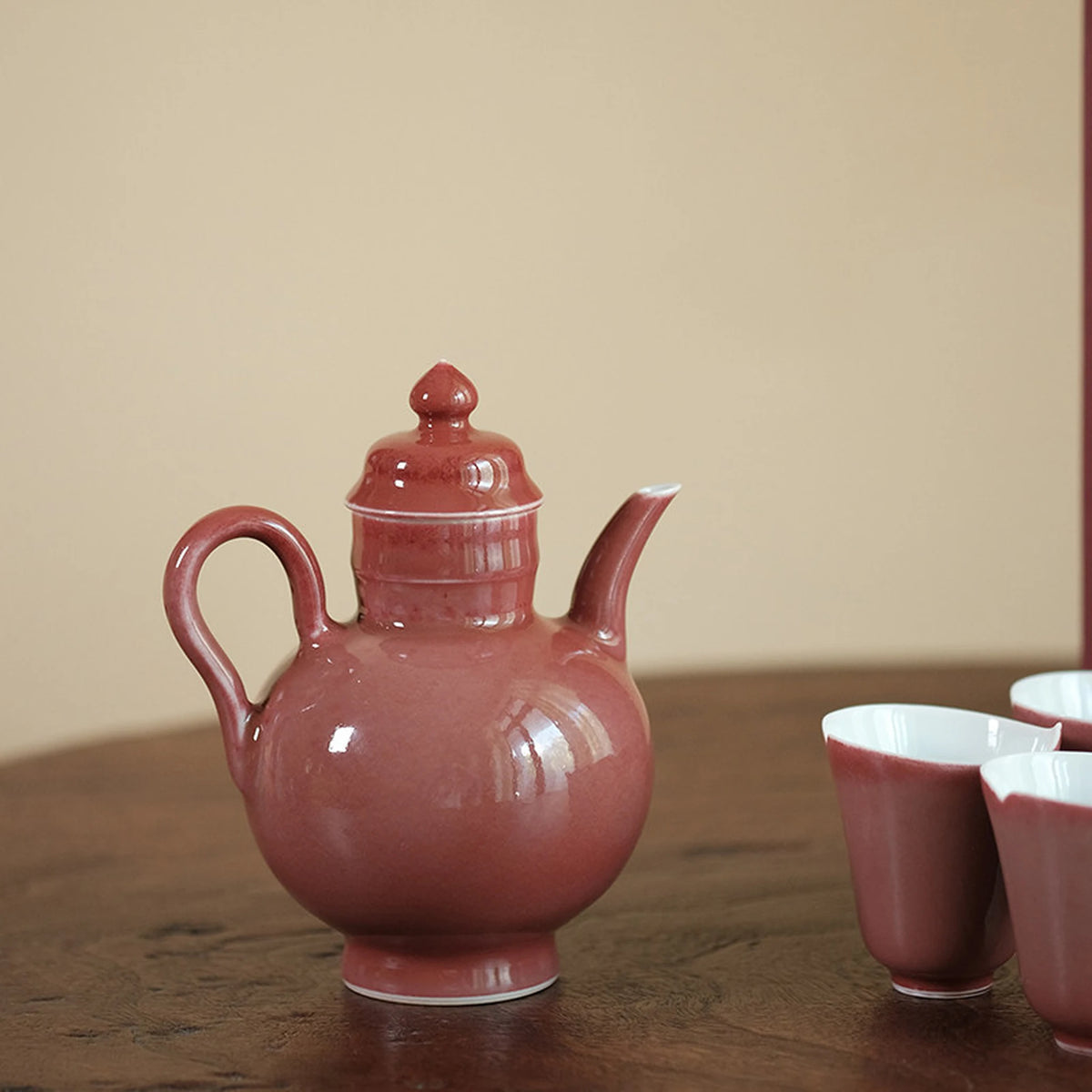 Rose glaze teapot with matching tea cups on a wooden table